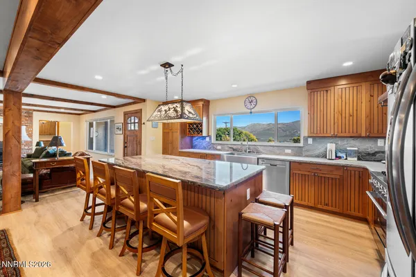 a kitchen with stainless steel appliances granite countertop table chairs sink and cabinets