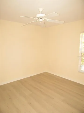 an empty room with windows and fan