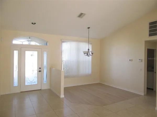 an empty room with chandelier fan and windows