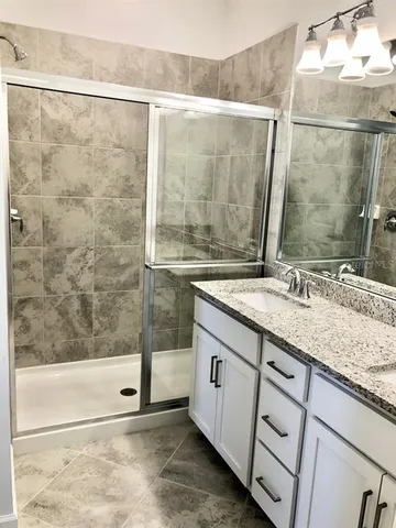 a bathroom with a granite countertop sink a mirror and a shower