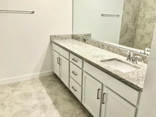 a bathroom with a granite countertop sink and a mirror