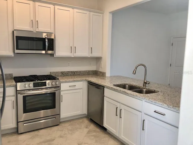 a kitchen with white cabinets and stainless steel appliances