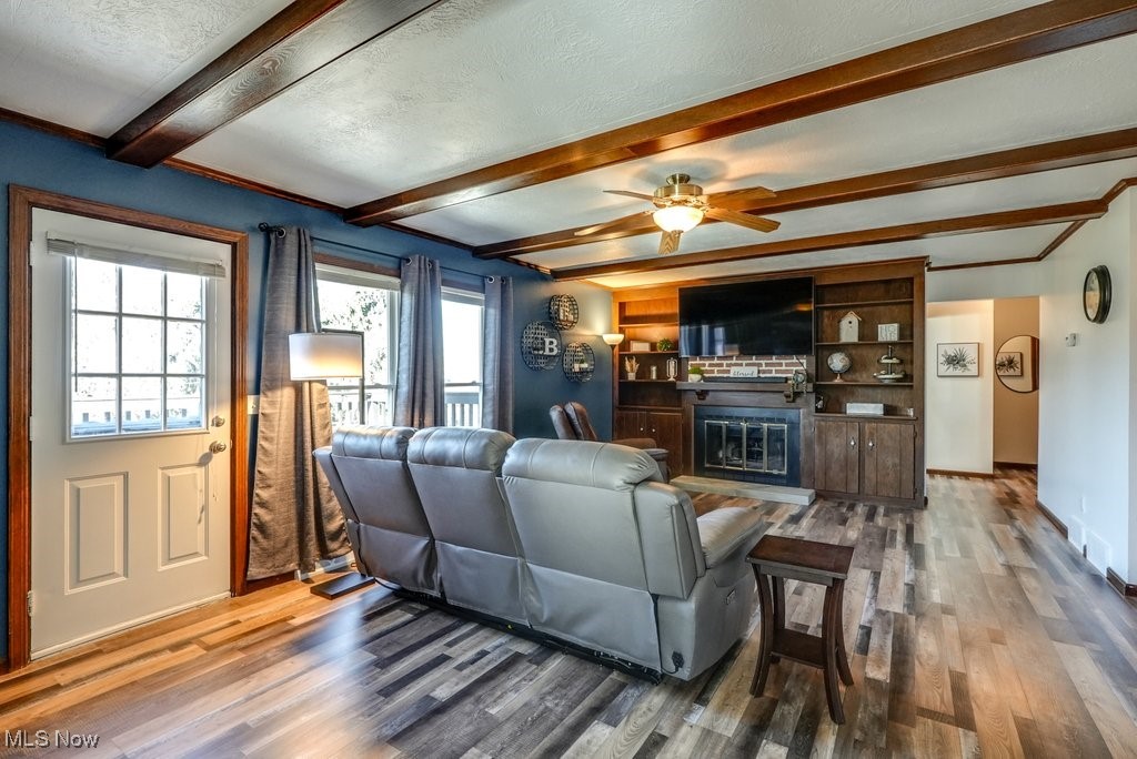 1157 Bass Circle Northwest Canton, OH 44708 - Photo 4 of 31 Living room with a glass covered fireplace, beam ceiling, a textured ceiling, and wood finished floors