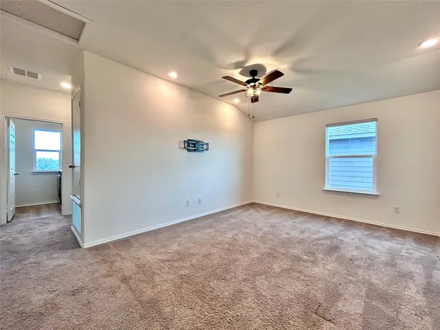 an empty room with chandelier fan and windows