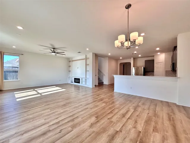 a view of a room with wooden floor kitchen view and a chandelier