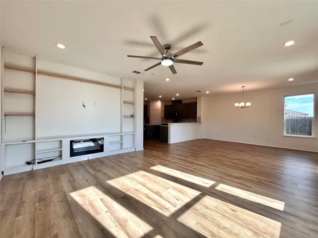 a view of a room with kitchen island stainless steel appliances wooden floor and window