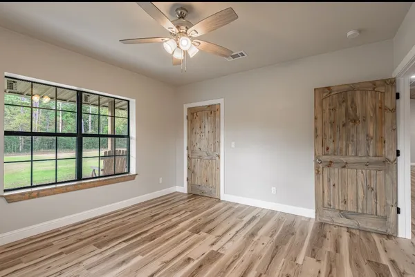 a view of empty room with wooden floor and fan