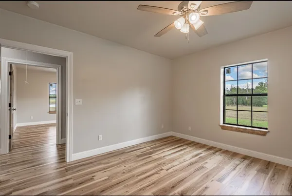 a view of an empty room with a window and wooden floor