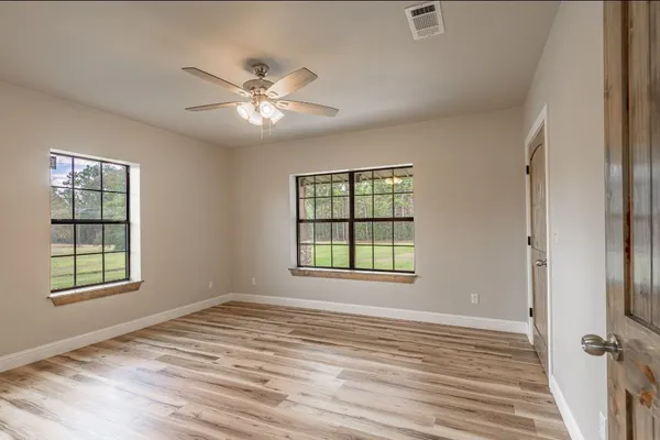 a view of a livingroom with a chandelier fan and wooden floor