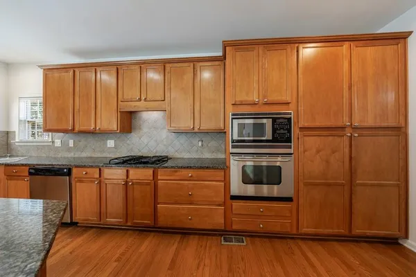 a room with kitchen island granite countertop a sink and wooden floors
