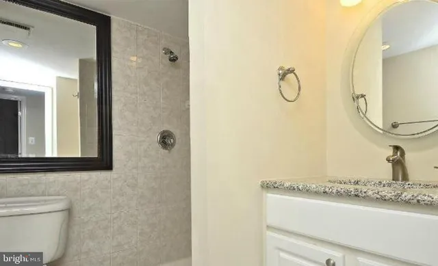 a bathroom with a granite countertop sink a mirror and a shower