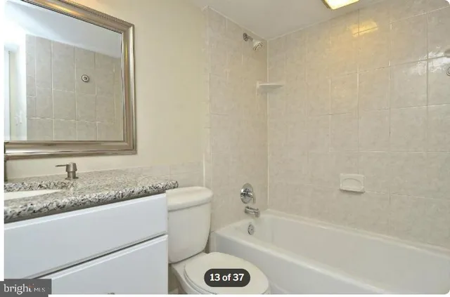 a bathroom with a granite countertop sink mirror toilet and bathtub