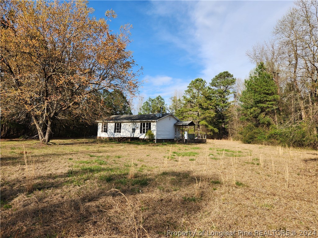 5470 Wade-Stedman Road Wade, NC 28395 - Photo 1 of 6 a house with a field of trees in the background