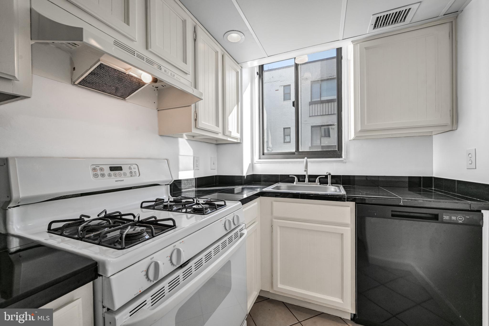 2610 Tunlaw Road Northwest, Unit 104 Washington, DC 20007 - Photo 15 of 20 a white kitchen with stainless steel appliances a sink a stove and cabinets
