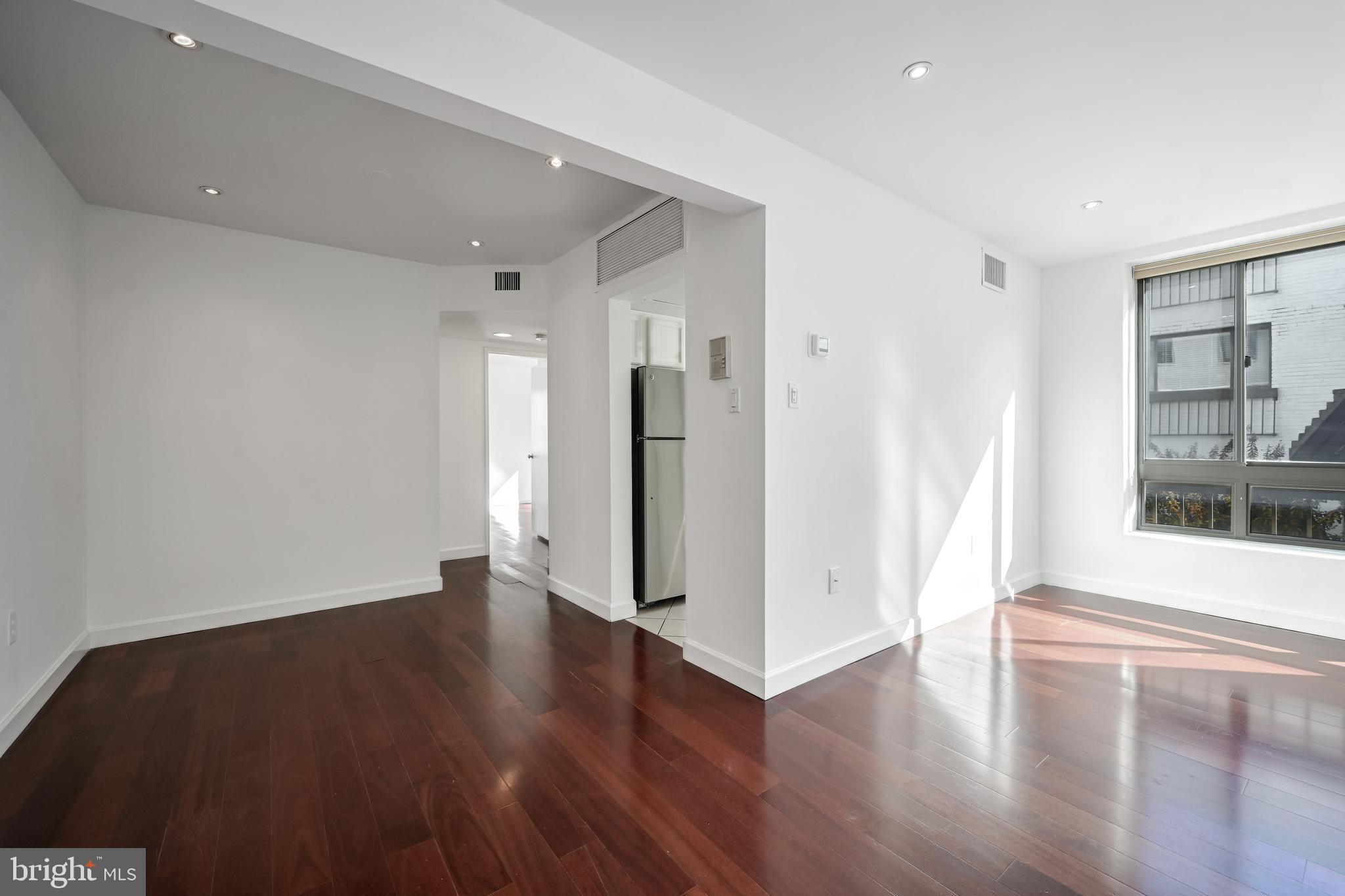 2610 Tunlaw Road Northwest, Unit 104 Washington, DC 20007 - Photo 3 of 20 a view of an empty room with wooden floor and a window