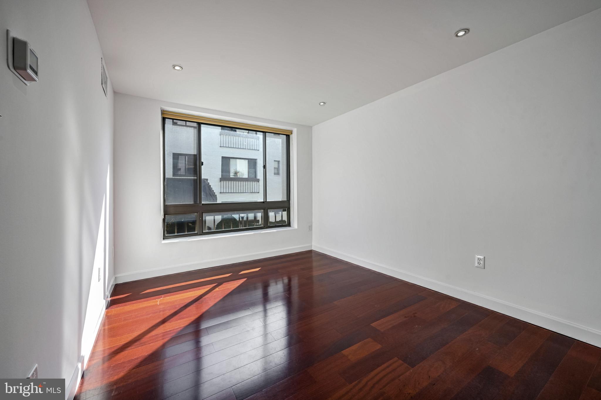 2610 Tunlaw Road Northwest, Unit 104 Washington, DC 20007 - Photo 7 of 20 a view of an empty room with a window and wooden floor