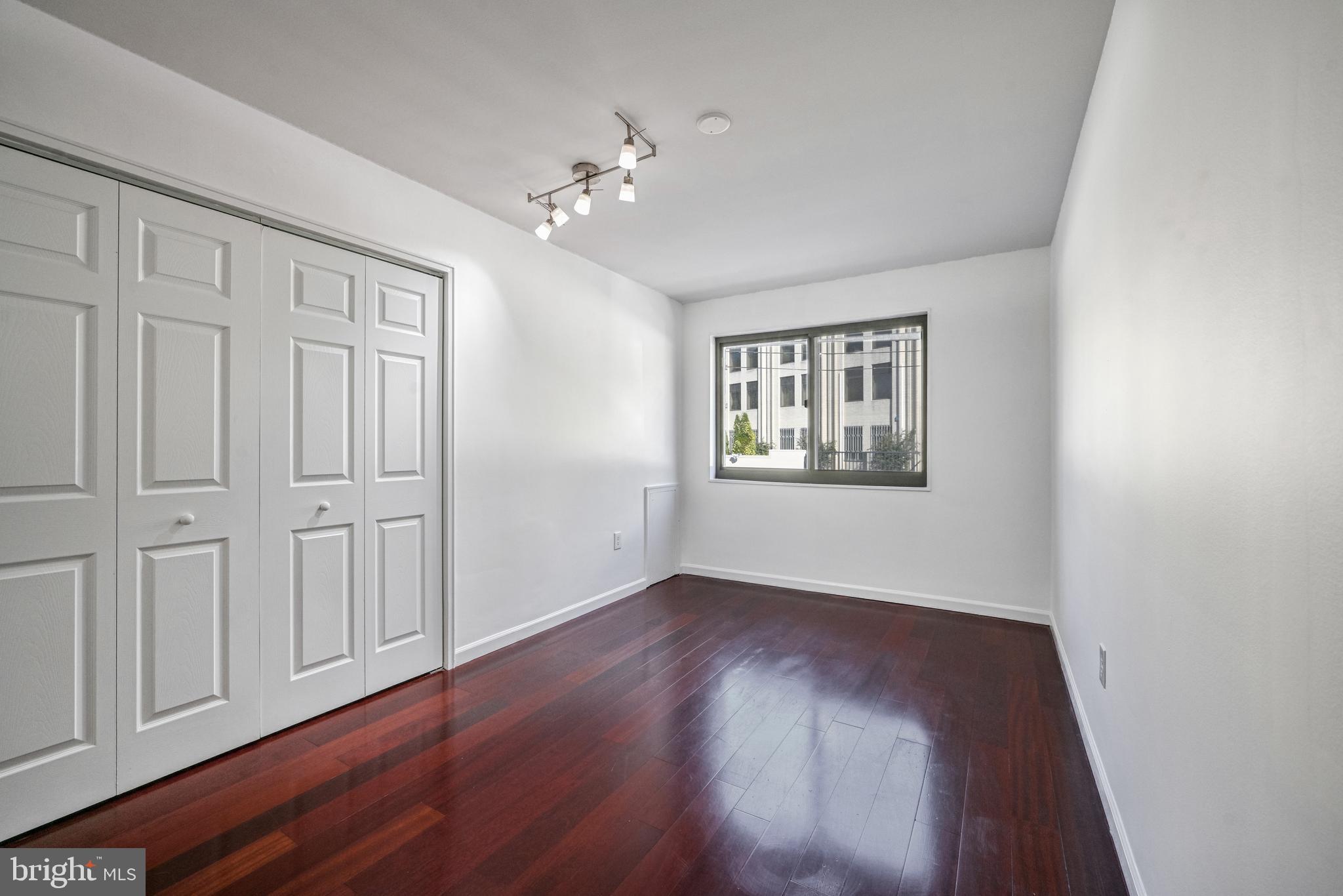 2610 Tunlaw Road Northwest, Unit 104 Washington, DC 20007 - Photo 9 of 20 a view of an empty room with wooden floor and a window