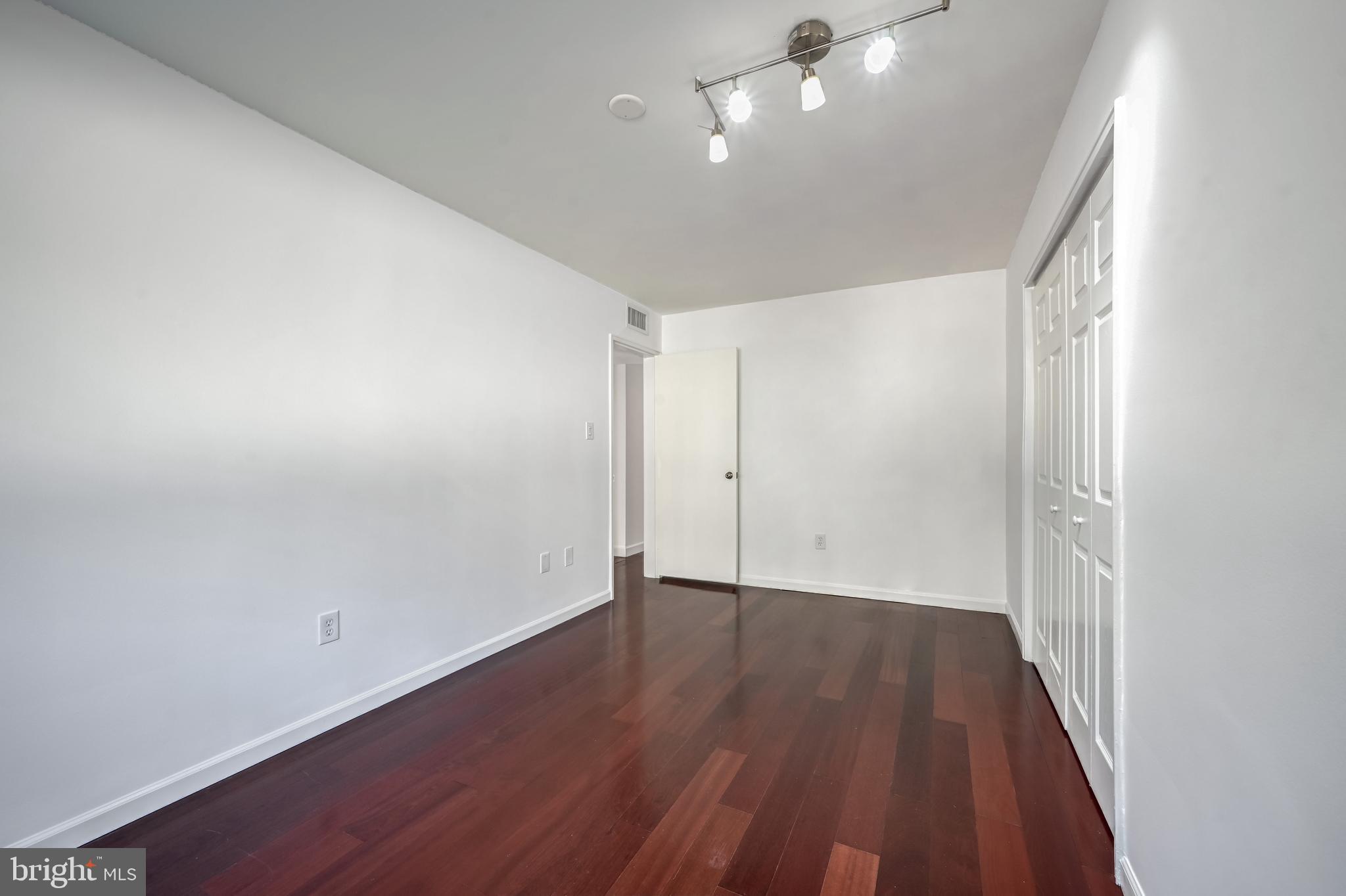 2610 Tunlaw Road Northwest, Unit 104 Washington, DC 20007 - Photo 10 of 20 an empty room with wooden floor and windows