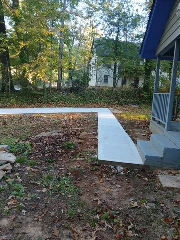 a view of a yard with plants and large trees