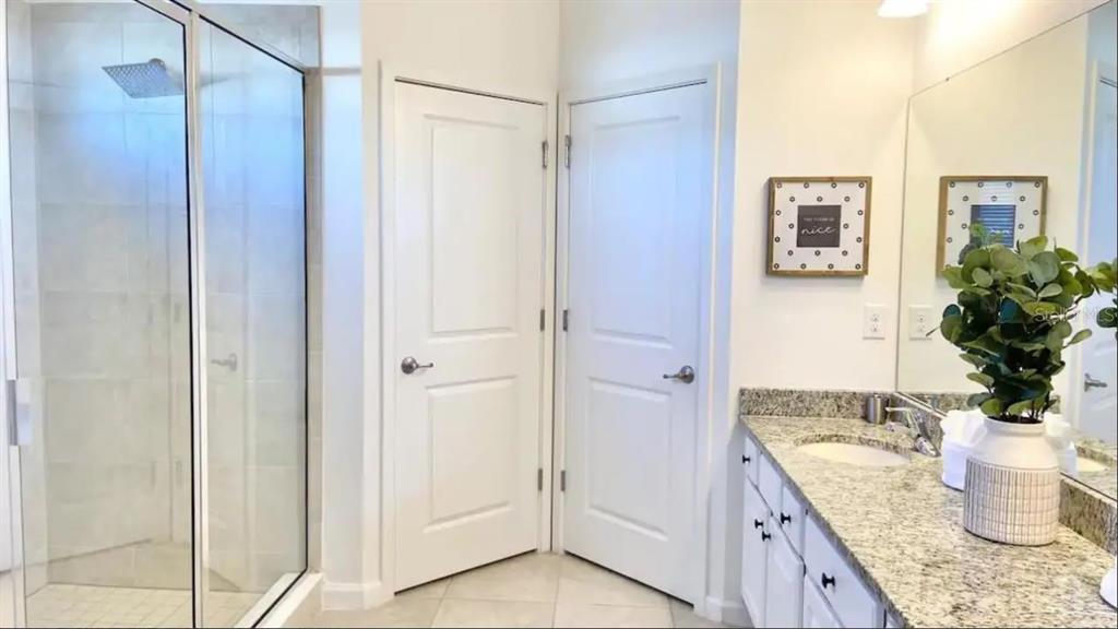 2676 Calistoga Avenue Kissimmee, FL 34741 - Photo 17 of 30 a bathroom with a granite countertop sink a mirror and shower