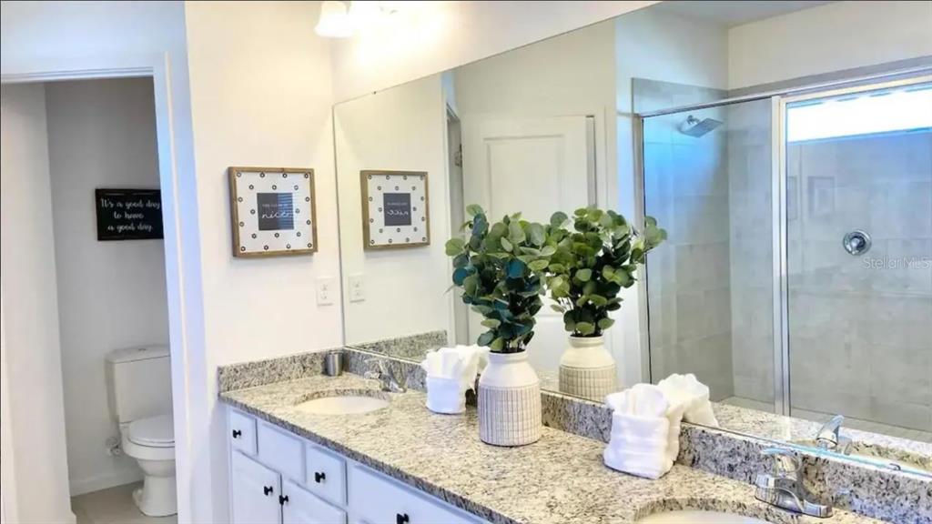 2676 Calistoga Avenue Kissimmee, FL 34741 - Photo 18 of 30 a bathroom with a granite countertop sink a toilet and shower