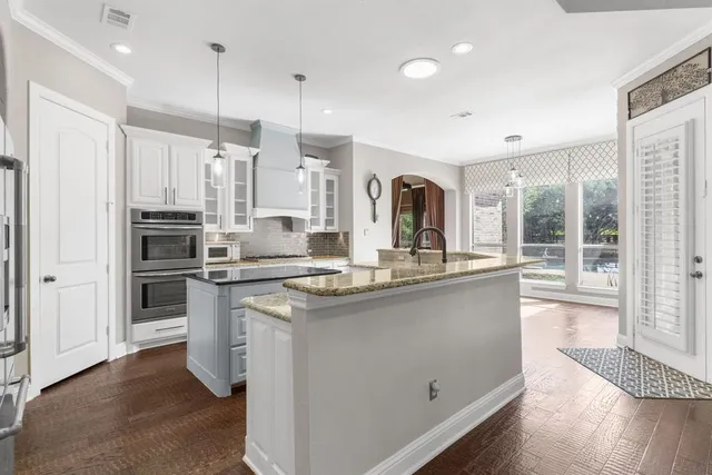 a kitchen with stainless steel appliances granite countertop a sink a stove a refrigerator and island with wooden floor