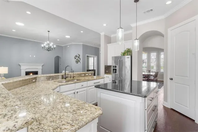 a large kitchen with kitchen island a chandelier and living room view