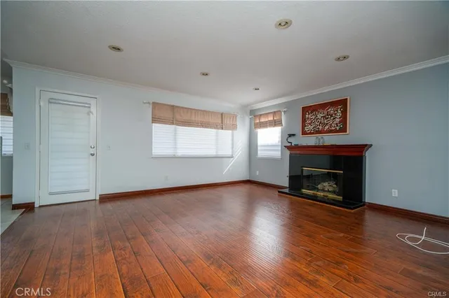 a view of an empty room with wooden floor fireplace and a window