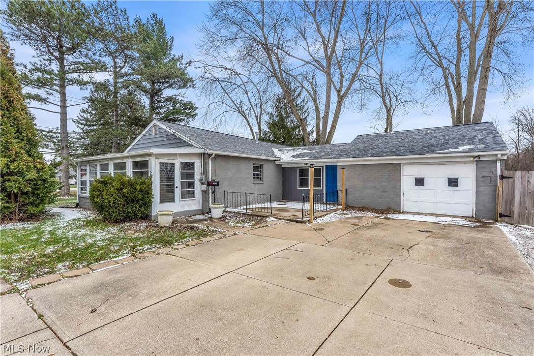 7320 Avon Belden Road North Ridgeville, OH 44039 - Photo 1 of 33 View of front facade with a garage, concrete driveway, roof with shingles, and a sunroom