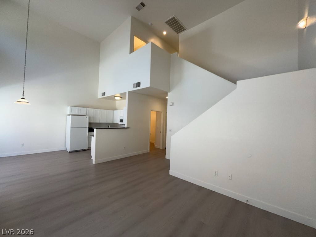 4915 East Russell Road, Unit 147 Las Vegas, NV 89120 - Photo 5 of 14 Unfurnished living room featuring dark wood-style flooring and a high ceiling