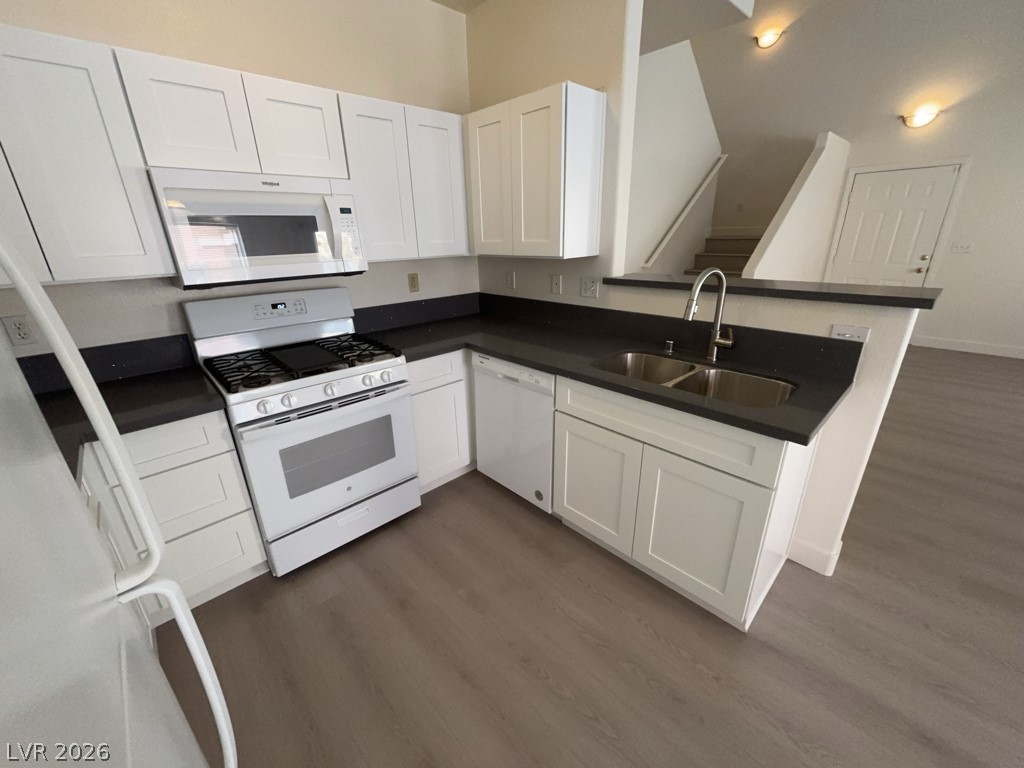 4915 East Russell Road, Unit 147 Las Vegas, NV 89120 - Photo 8 of 14 Kitchen featuring dark countertops, white appliances, dark wood-type flooring, and white cabinets