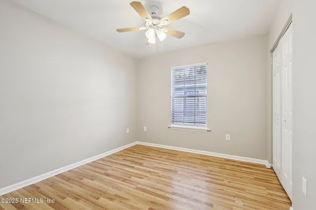 a view of an empty room with window and a ceiling fan