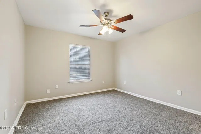 an empty room with a window and ceiling fan