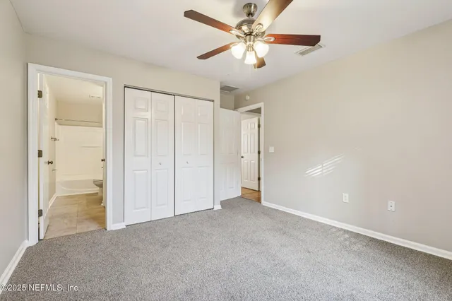 an empty room with closet and a chandelier fan