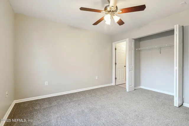 an empty room with closet and a chandelier fan