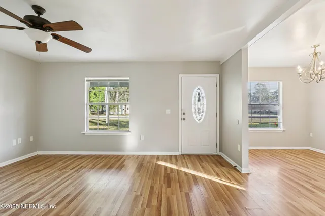 an empty room with wooden floor cabinet and windows