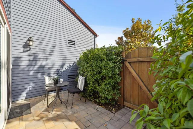 a backyard of a house with table and chairs and potted plants