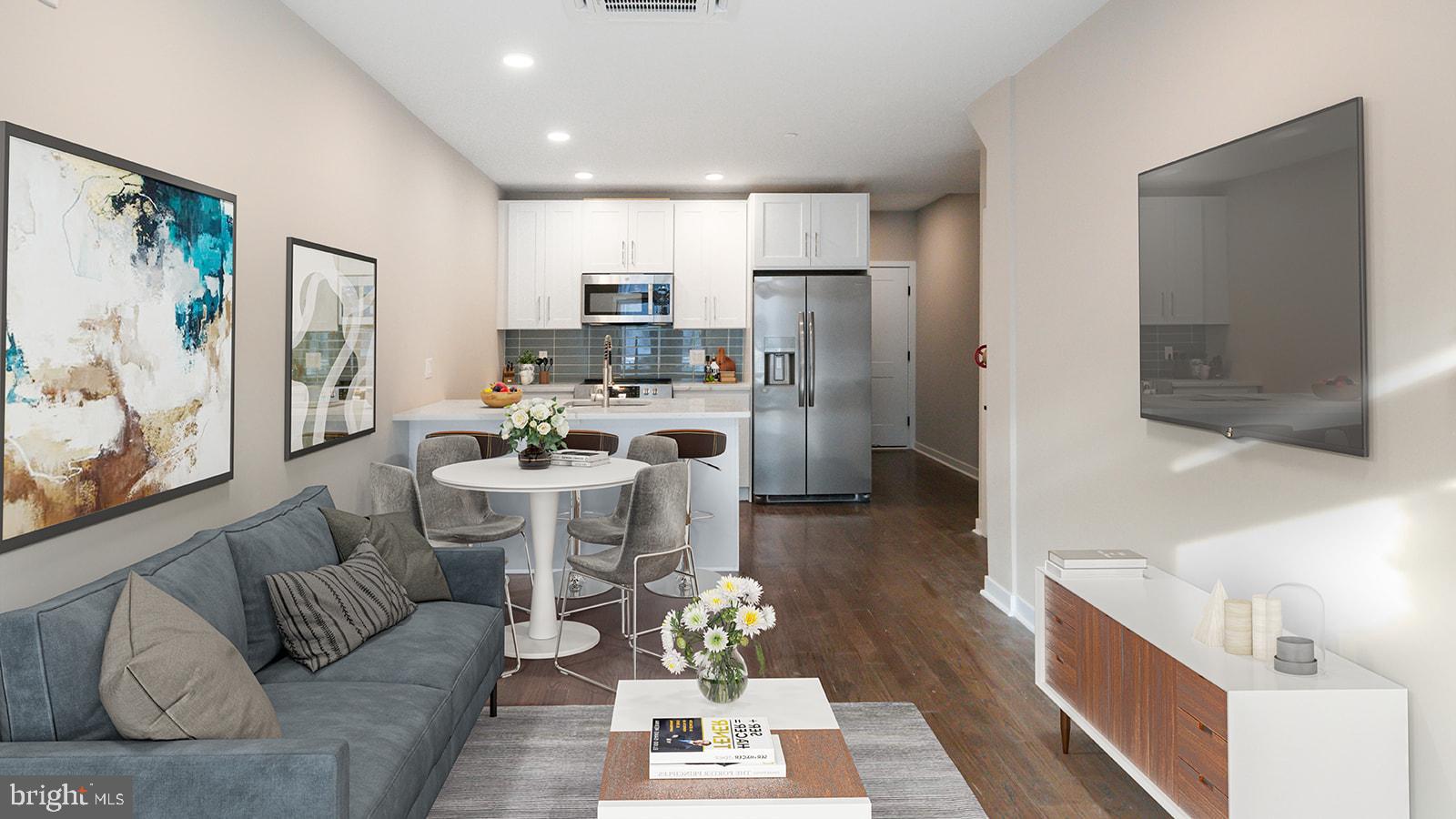 a living room with stainless steel appliances furniture and a view of kitchen