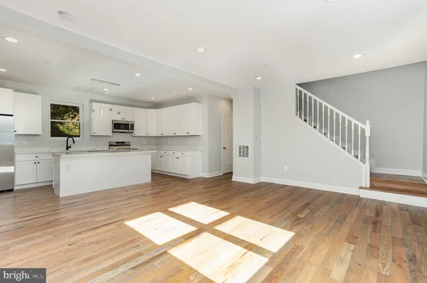 a kitchen with stainless steel appliances granite countertop grey cabinets a stove a sink and a microwave