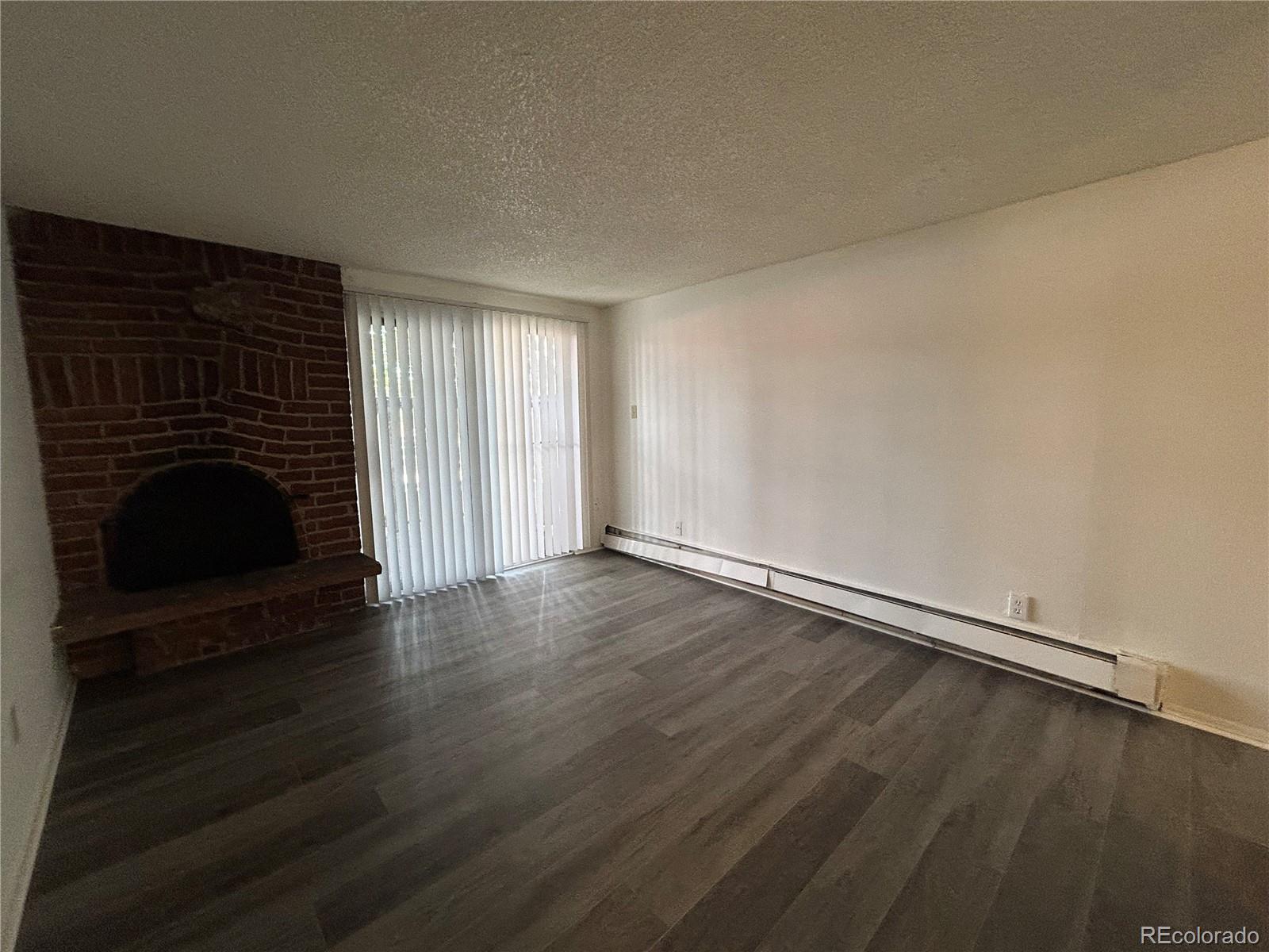 1306 South Parker Road, Unit 167 Denver, CO 80231 - Photo 6 of 14 an empty room with wooden floor fireplace and windows