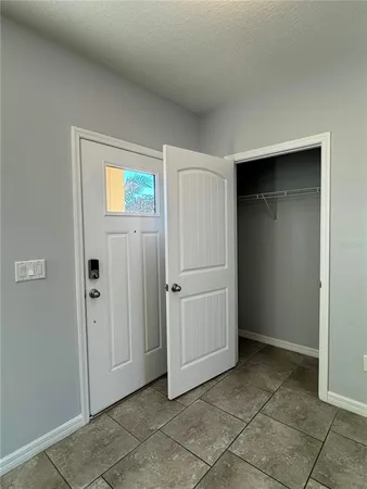 a view of an empty room with a window and a kitchen
