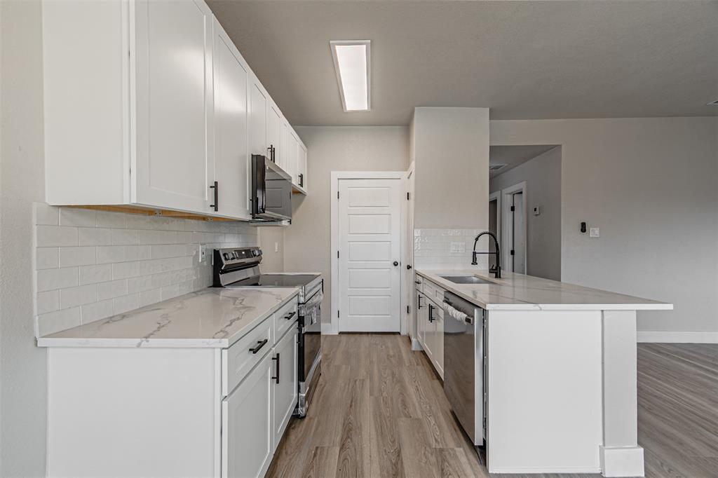 4107 Esters Road, Unit 807 Irving, TX 75038 - Photo 1 of 1 Kitchen with light wood-style flooring, a sink, stainless steel appliances, a peninsula, and white cabinets