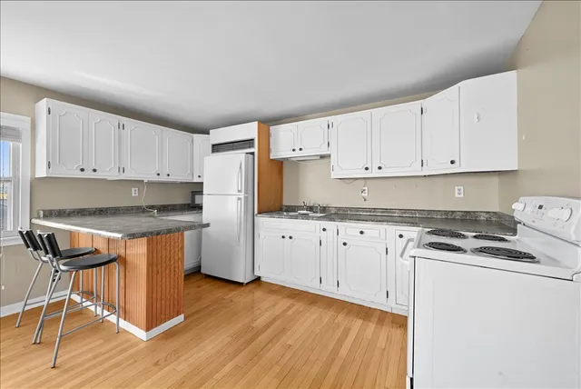 a kitchen with granite countertop wooden cabinets and white appliances