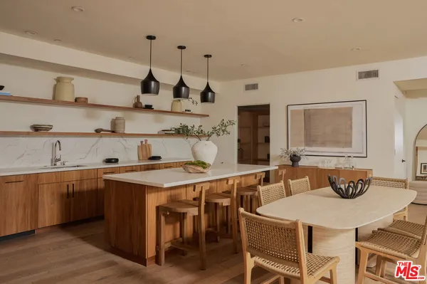 a open kitchen with stainless steel appliances granite countertop a sink a stove a dining table and chairs