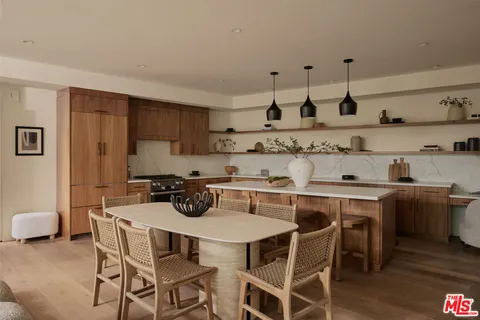 a kitchen with stainless steel appliances a table and chairs in it