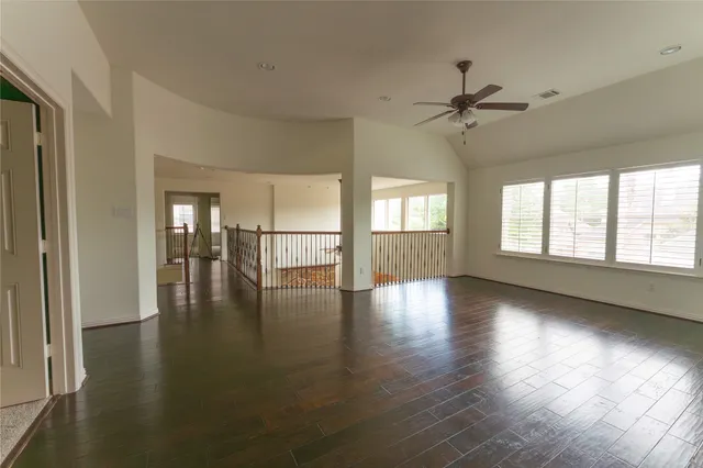 a view of empty room with wooden floor and fan
