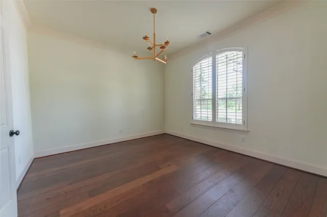 an empty room with wooden floor ceiling fan and windows