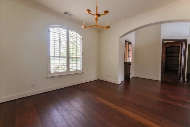 an empty room with wooden floor chandelier and windows
