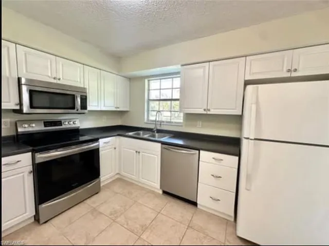 a kitchen with granite countertop white cabinets and white appliances