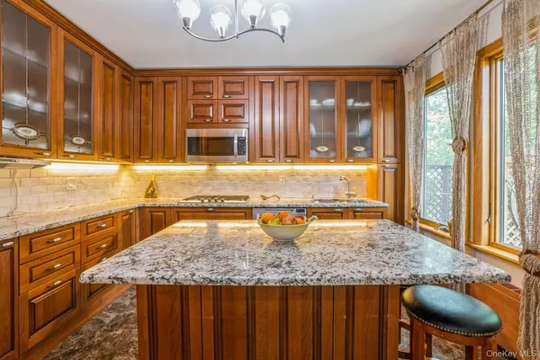 a kitchen with kitchen island granite countertop wooden cabinets a sink and a large window